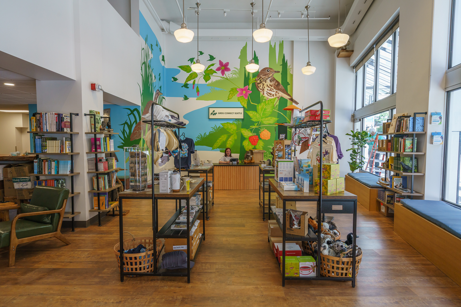 Photo features a Sandhill Crane, a large bird, standing on one leg with wings open.