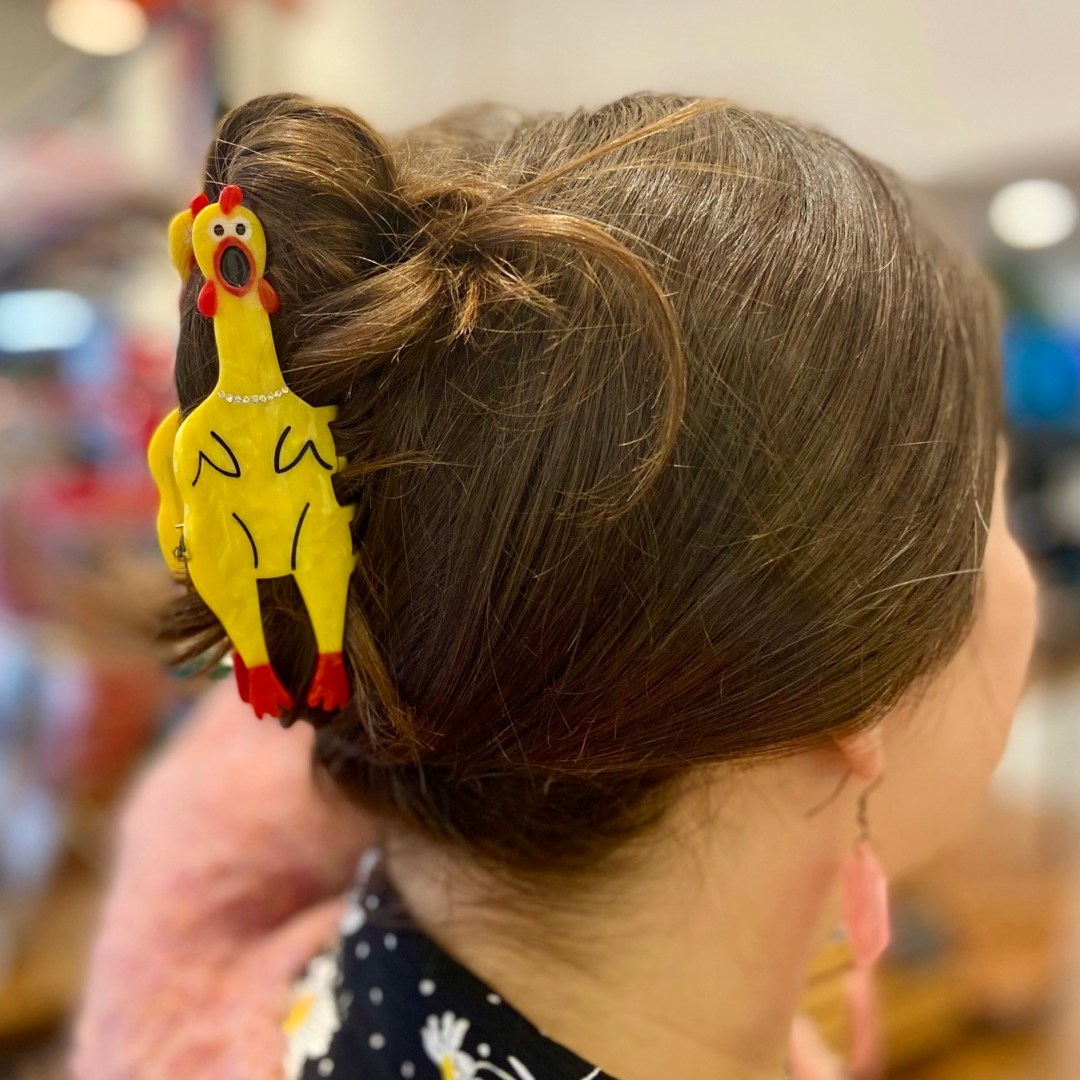 Photo features a yellow plastic chicken claw clip in someone's hair.