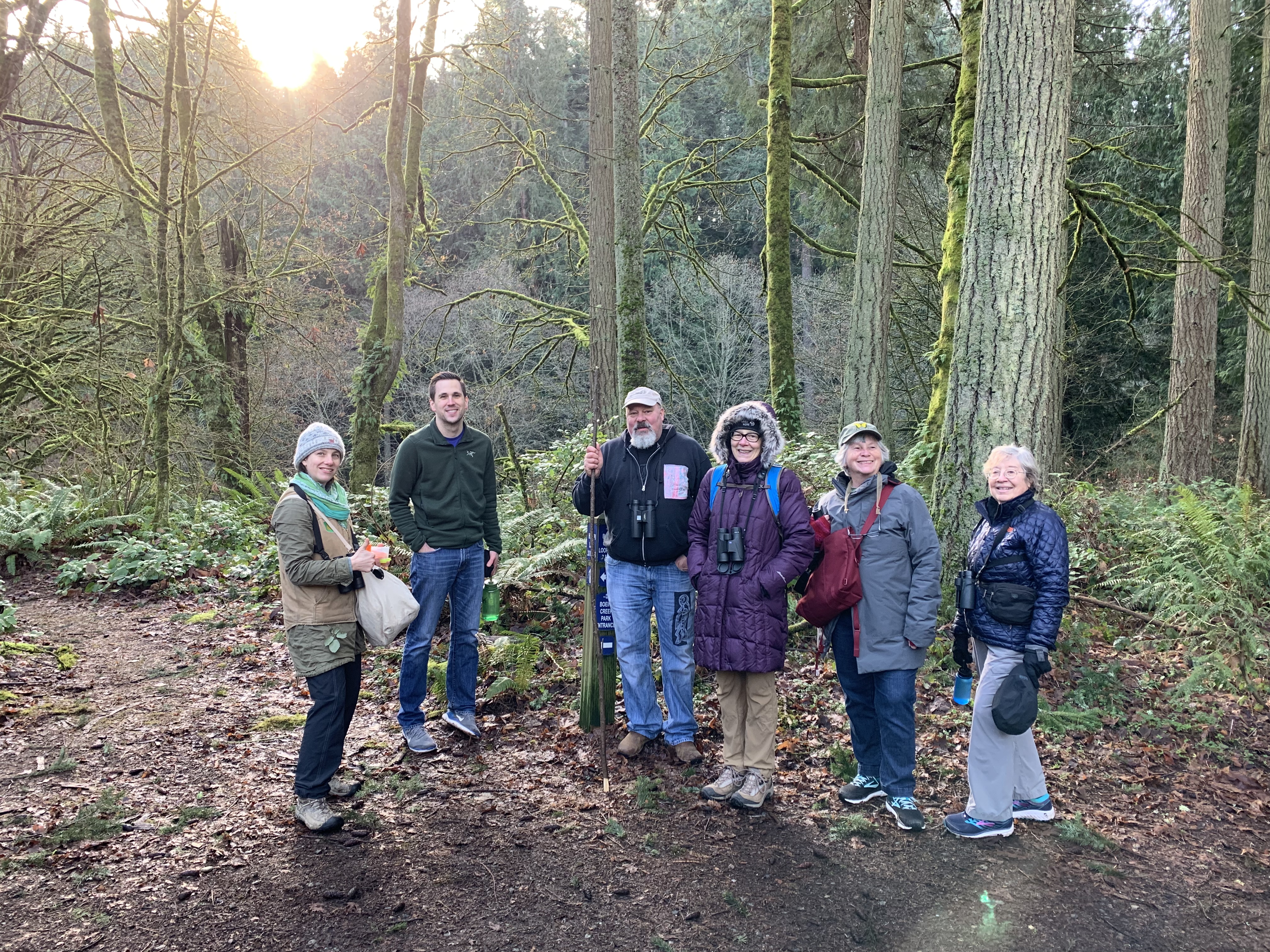 Photo features a Sandhill Crane, a large bird, standing on one leg with wings open.