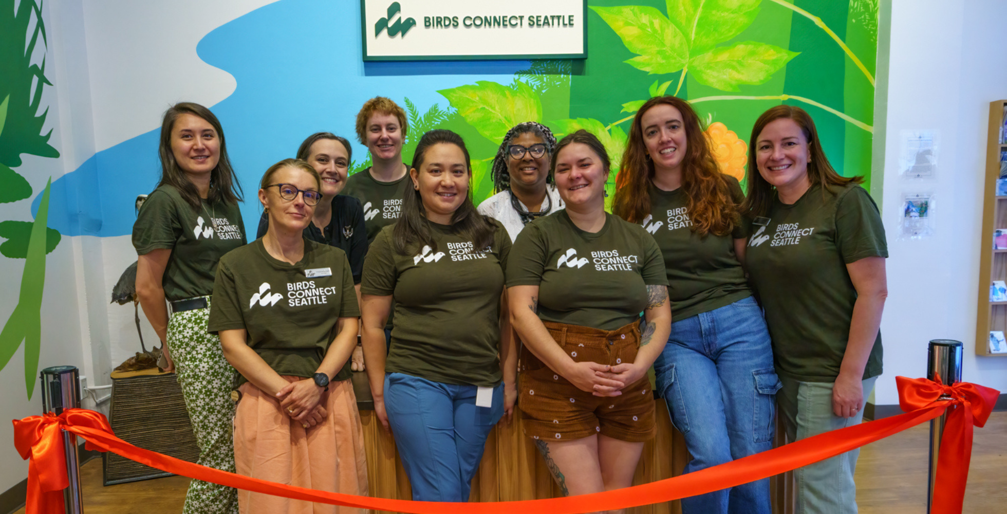 Photo features a Sandhill Crane, a large bird, standing on one leg with wings open.